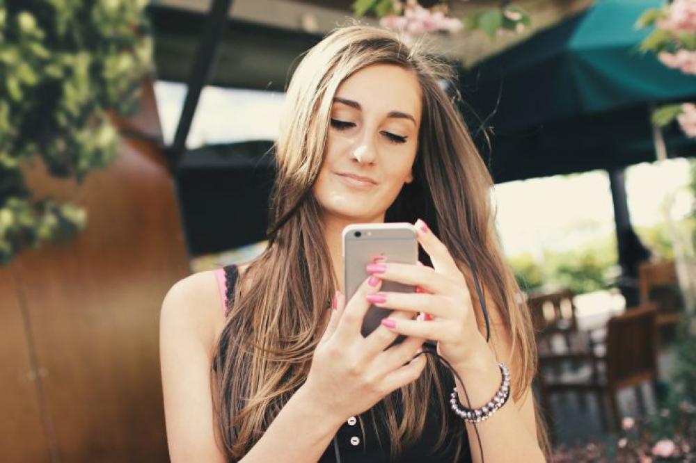 A young girl uses an app for a chat on a smartphone outdoors A young girl uses an app for a chat on a smartphone outdoors