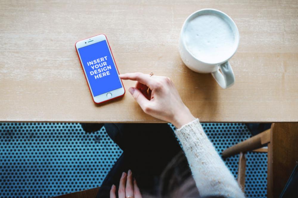 Free Mockup. Modern smartphone on the table with a hand of a woman in a cafe Free Mockup. Modern smartphone on the table with a hand of a woman in a cafe