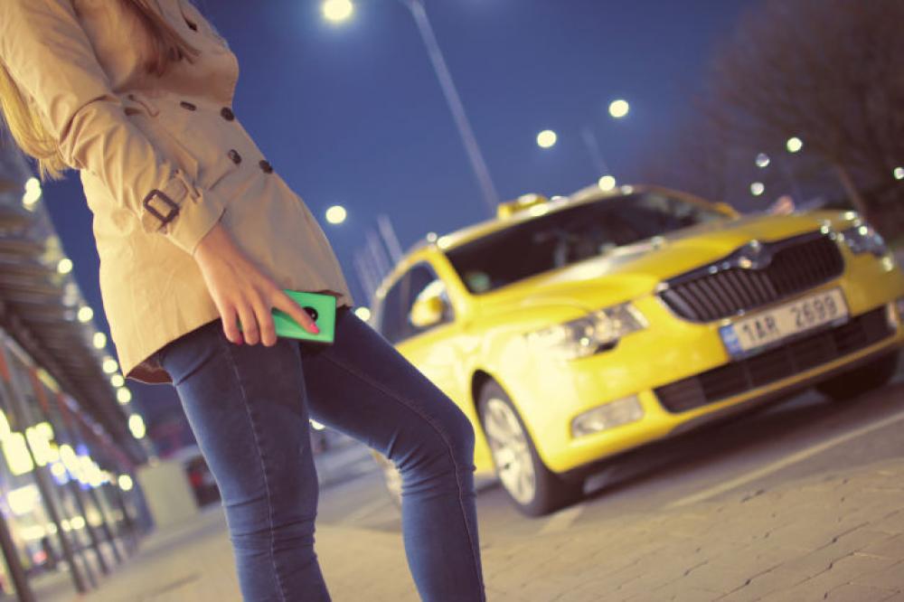Woman waiting for a taxi with phone in hand Woman waiting for a taxi with phone in hand