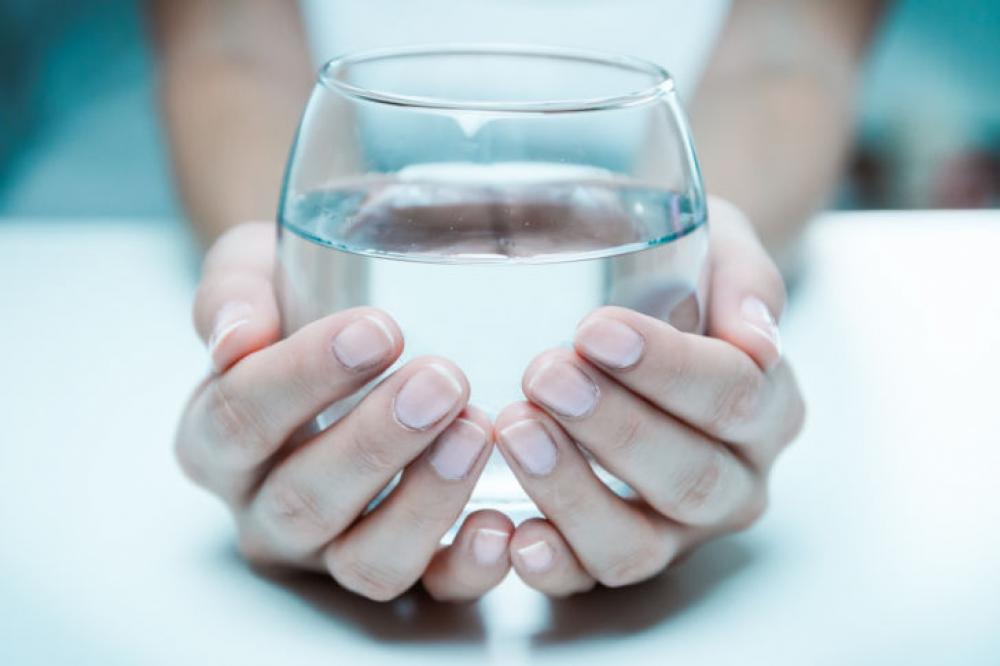 Female hand holding a glass of clean water, close-up. Female hand holding a glass of clean water, close-up.