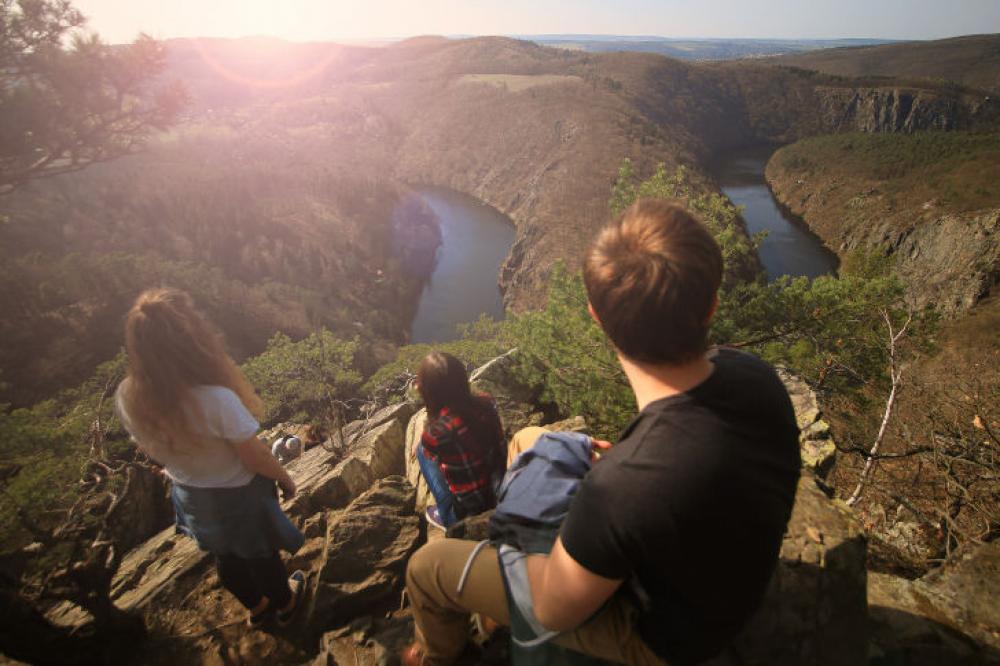 A group of young people in the beautiful view from the rocks at sunset A group of young people in the beautiful view from the rocks at sunset