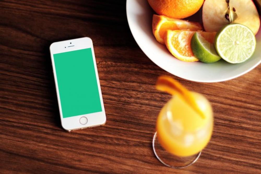 Smartphone, a bowl of fruit and a drink on the wooden table Smartphone, a bowl of fruit and a drink on the wooden table