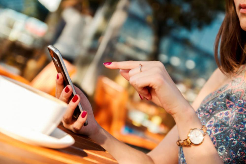 Young girl typing message on her smartphone in the restaurant garden Young girl typing message on her smartphone in the restaurant garden