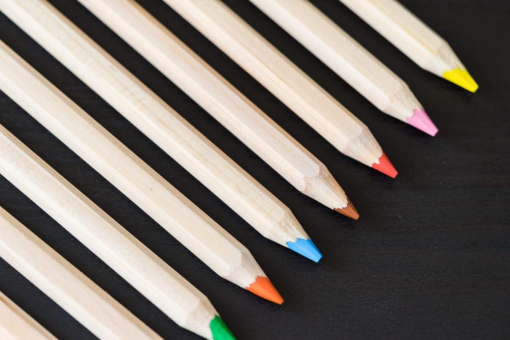 Long Colored Pencils in a Row on Black Desk Long Colored Pencils in a Row on Black Desk