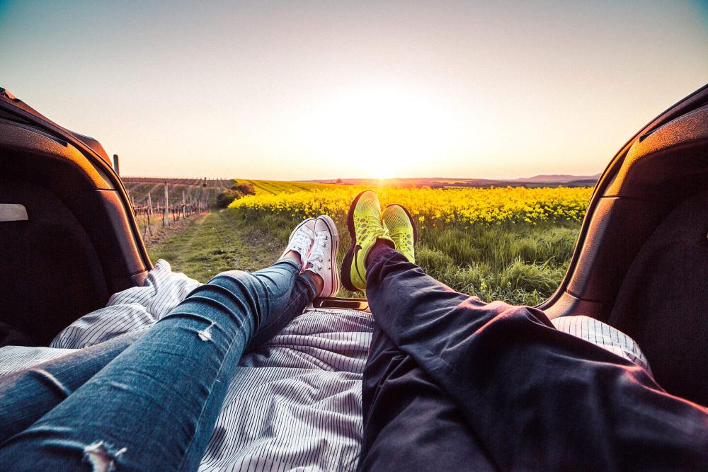 Young Couple Enjoying Romantic Sunset from Car Trunk Young Couple Enjoying Romantic Sunset from Car Trunk
