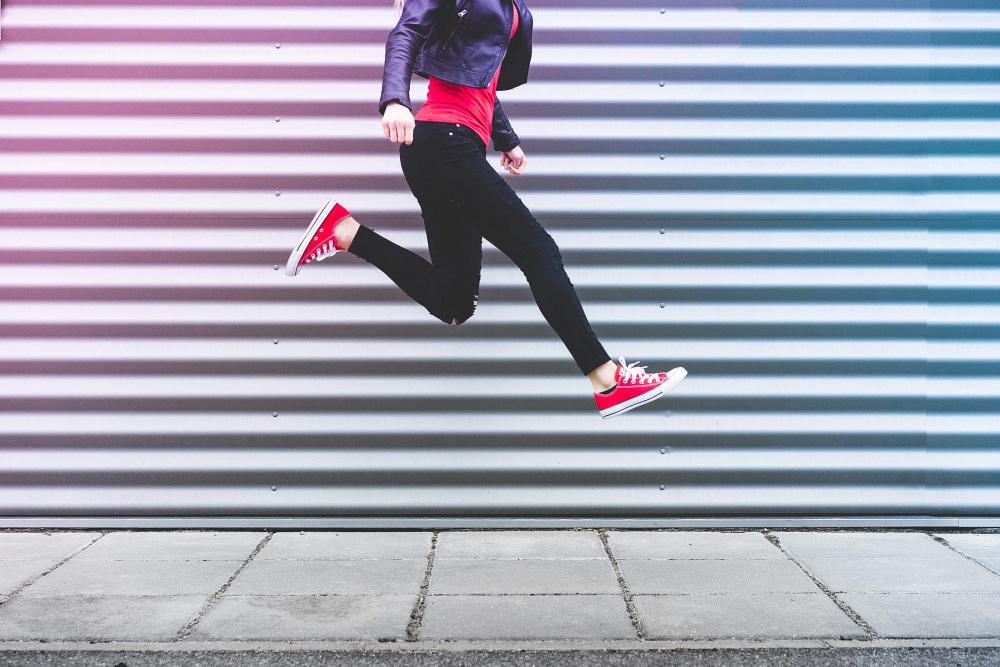 Young Happy Woman Jumping in Front of Metal Wall Young Happy Woman Jumping in Front of Metal Wall