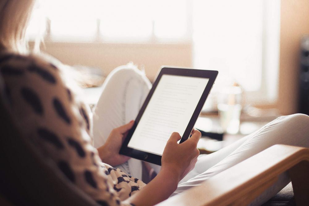 Young Woman Reading a Book on Her iPad Young Woman Reading a Book on Her iPad