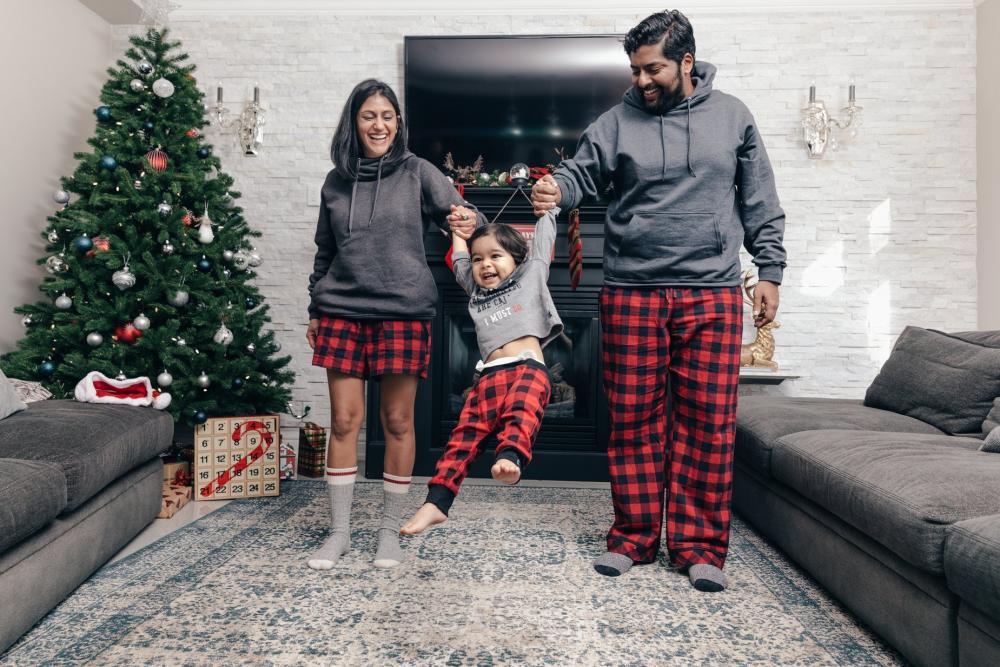 Happy Couple Swings Toddler On Christmas Morning Photo Happy Couple Swings Toddler On Christmas Morning Photo