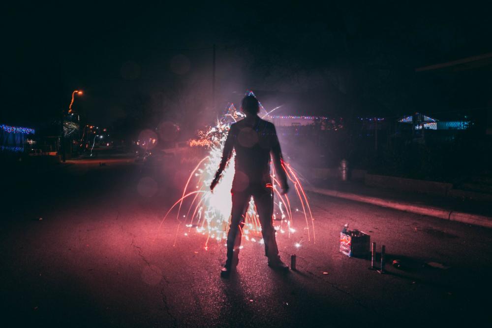 Man Setting Off Fireworks On Suburban Street Photo Man Setting Off Fireworks On Suburban Street Photo