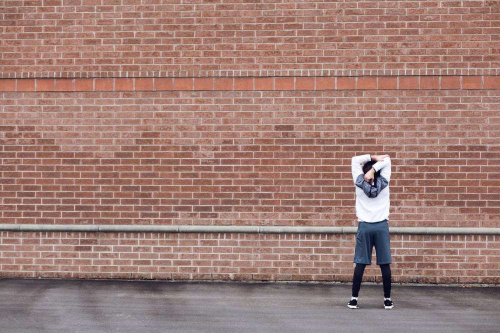 Runner Stretching By Brick Wall Photo Runner Stretching By Brick Wall Photo