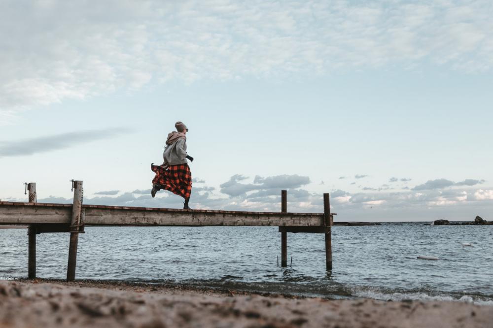 Young Woman In Autumn Clothing Running Across Dock Photo Young Woman In Autumn Clothing Running Across Dock Photo
