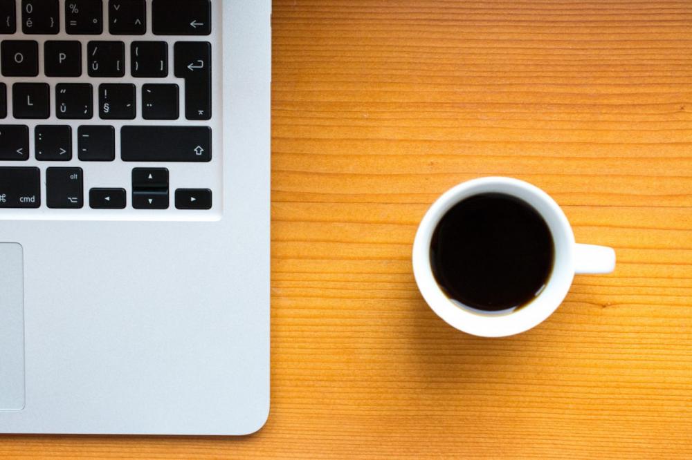 Macbook and black coffee in white cup on wood from the top Macbook and black coffee in white cup on wood from the top