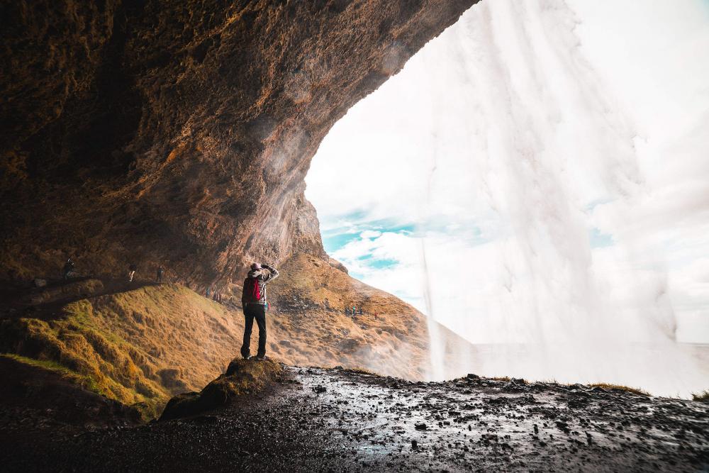 Woman Under Seljalandsfoss Waterfall, Iceland Woman Under Seljalandsfoss Waterfall, Iceland