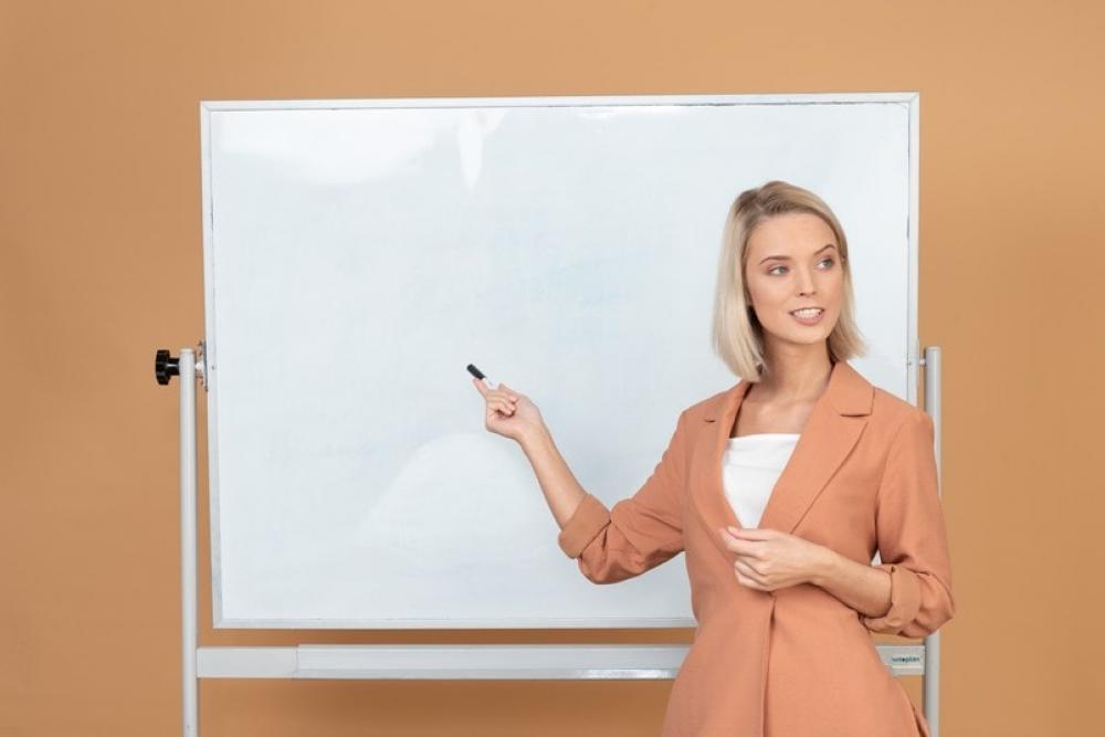 Attractive Woman Standing Next To A Whiteboard And Explaining Something Attractive Woman Standing Next To A Whiteboard And Explaining Something