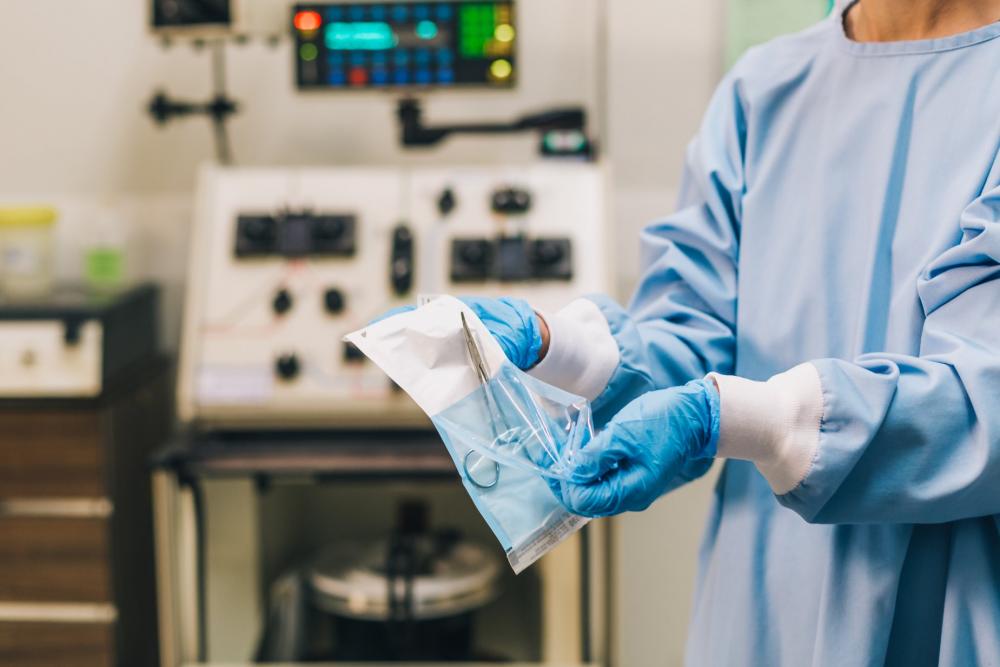 Medical Professional In Scrubs Unwraps Sterile Forceps Photo Medical Professional In Scrubs Unwraps Sterile Forceps Photo