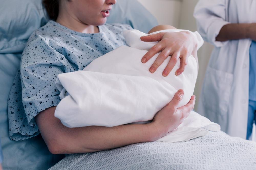 New Mother In Hospital Gown Embraces Her Baby Photo New Mother In Hospital Gown Embraces Her Baby Photo