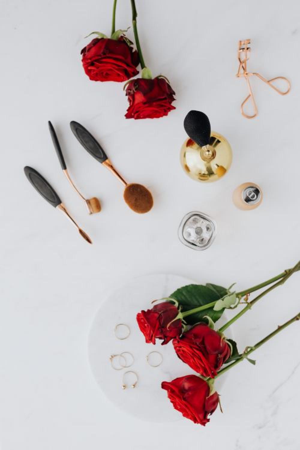 Red roses, gold jewellery and beauty accessories on white marble Red roses, gold jewellery and beauty accessories on white marble