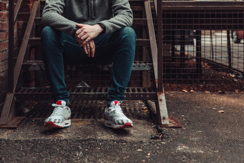 Man In Dark Denim And Fashion Sneakers Sitting On Stairwell Photo Man In Dark Denim And Fashion Sneakers Sitting On Stairwell Photo