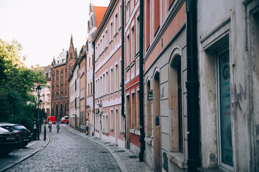 Two Cyclists Roll Down A Picturesque Cobbled Street Photo Two Cyclists Roll Down A Picturesque Cobbled Street Photo