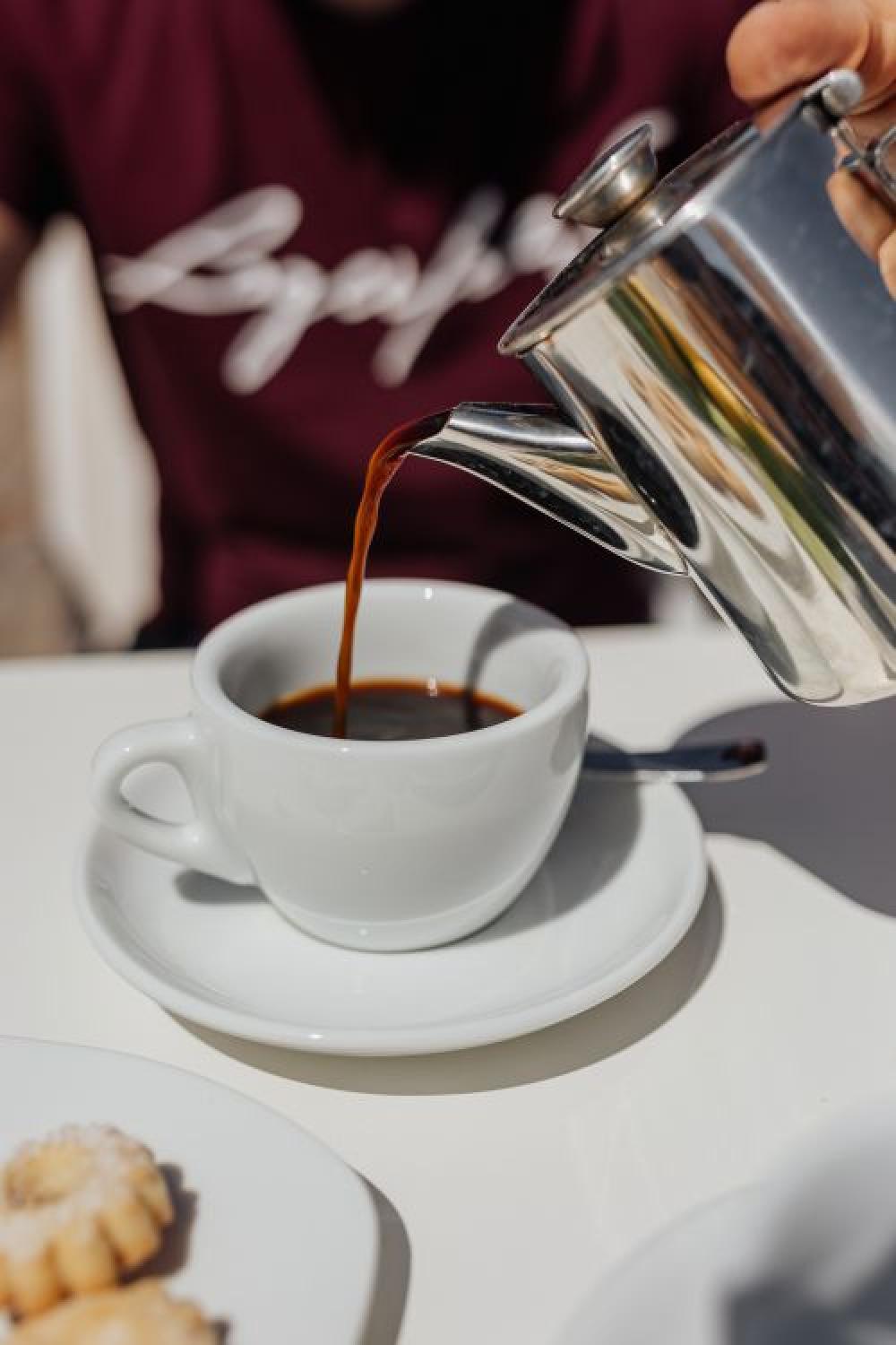 Pouring coffee into a cup. Silver kettles, Italian cookies. Pouring coffee into a cup. Silver kettles, Italian cookies.