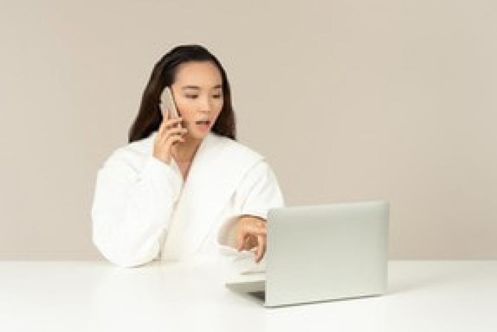 Young Asian Woman Talking On The Phone And Using Laptop Young Asian Woman Talking On The Phone And Using Laptop