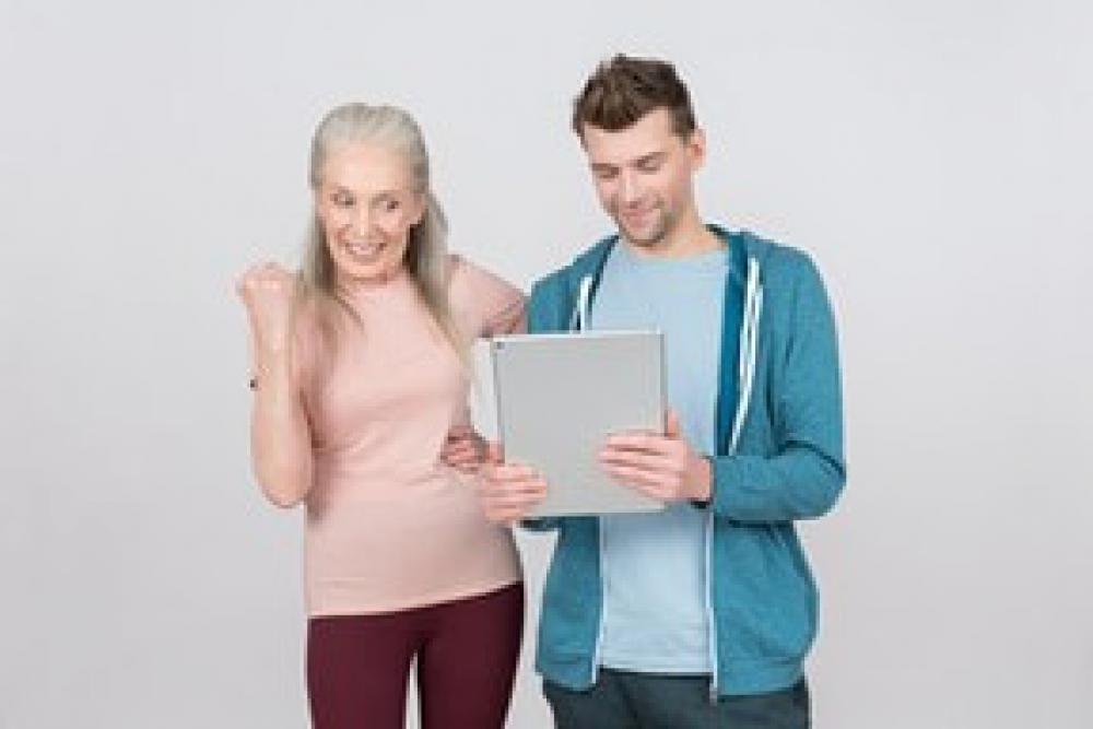 Excited Old Woman And Young Guy Looking At Sports Results On The Tablet Excited Old Woman And Young Guy Looking At Sports Results On The Tablet