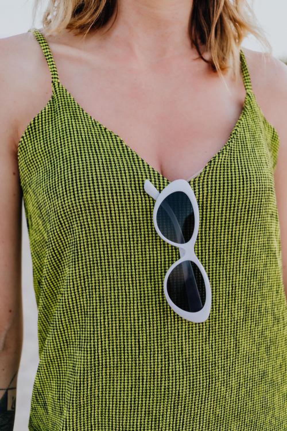 A woman in a green dress on the beach with white sunglasses A woman in a green dress on the beach with white sunglasses
