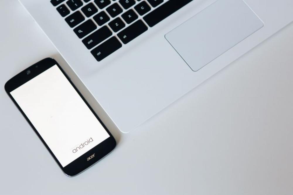White laptop with smartphone and headphones White laptop with smartphone and headphones