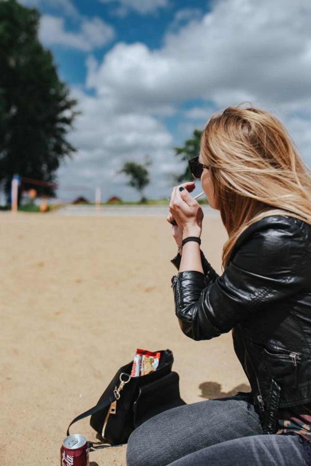 Young woman wearing a leather jacket and sunglasses on the beach Young woman wearing a leather jacket and sunglasses on the beach