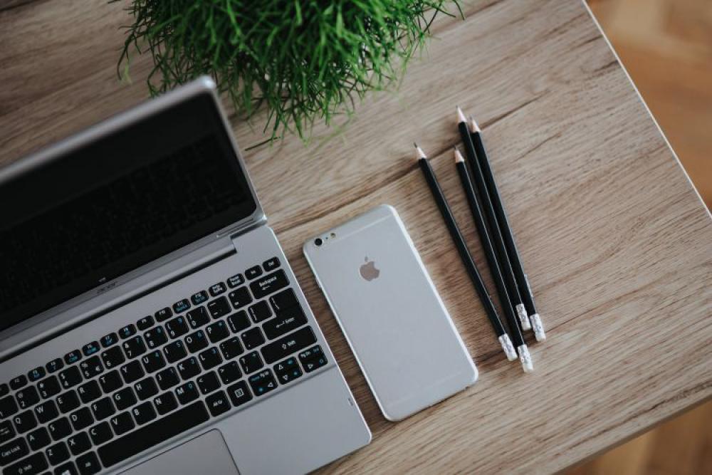 Silver Acer laptop on a wooden desk with a green plant, pencils and an Apple iPhone Silver Acer laptop on a wooden desk with a green plant, pencils and an Apple iPhone