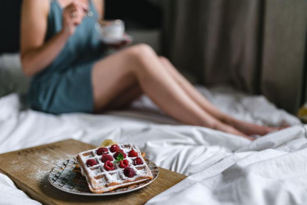 Breakfast in bed - waffles with raspberries and cup of coffee on the tray Breakfast in bed - waffles with raspberries and cup of coffee on the tray