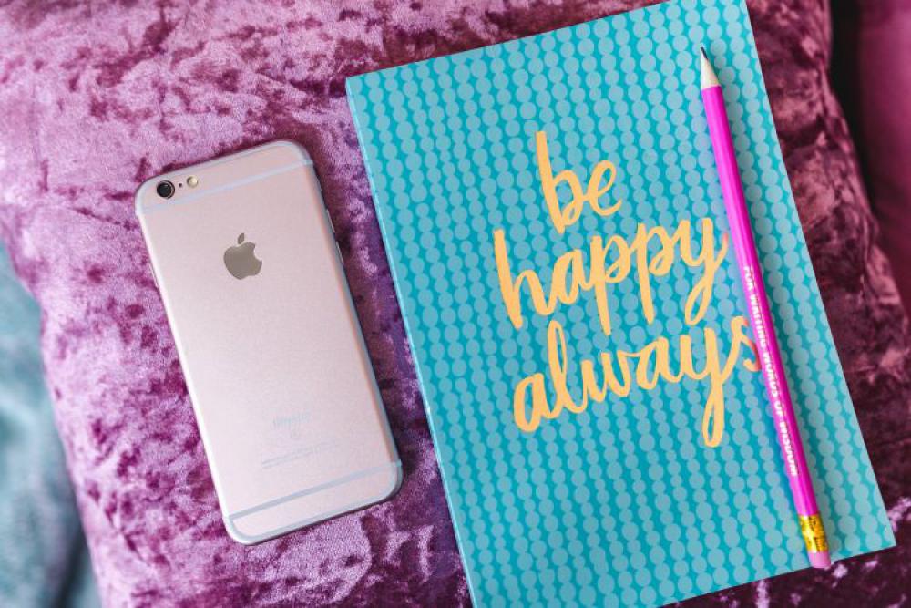 Blue notebook with a pink iPhone, headphones and a sweet bun Blue notebook with a pink iPhone, headphones and a sweet bun