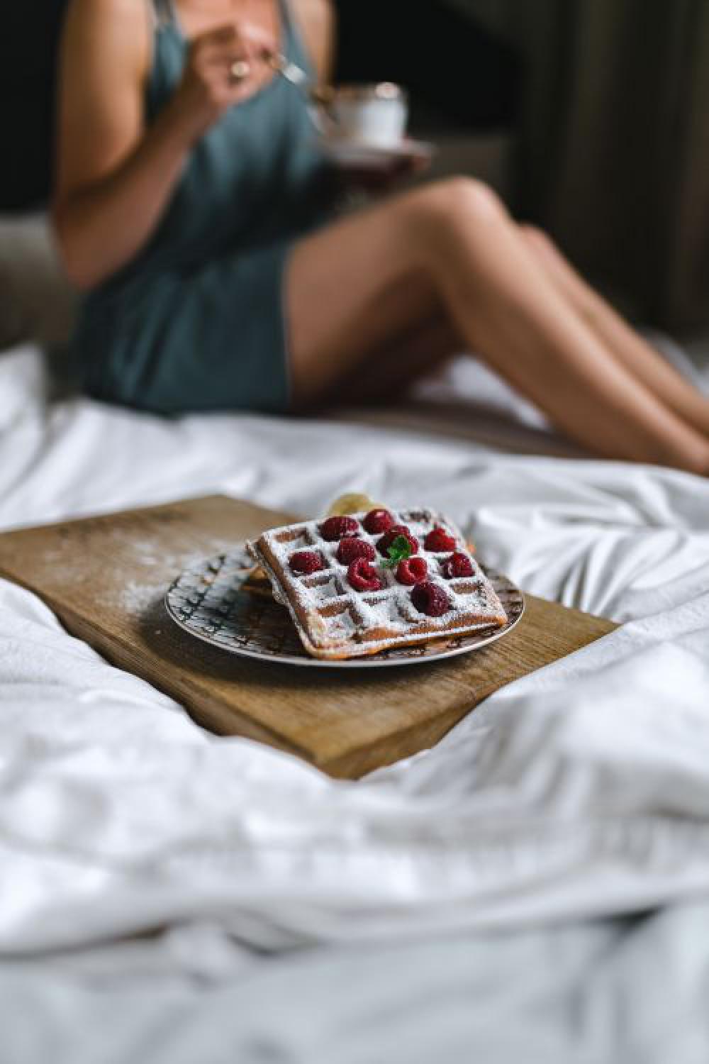 Breakfast in bed - waffles with raspberries and cup of coffee on the tray Breakfast in bed - waffles with raspberries and cup of coffee on the tray