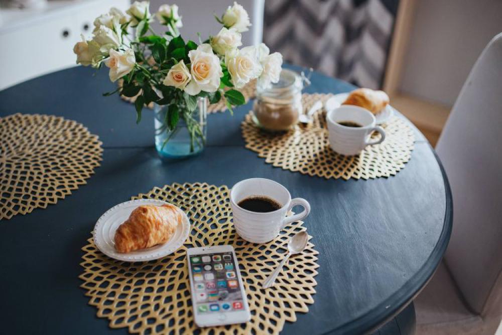 Round breakfast table with white flowers and golden coffee mats Round breakfast table with white flowers and golden coffee mats