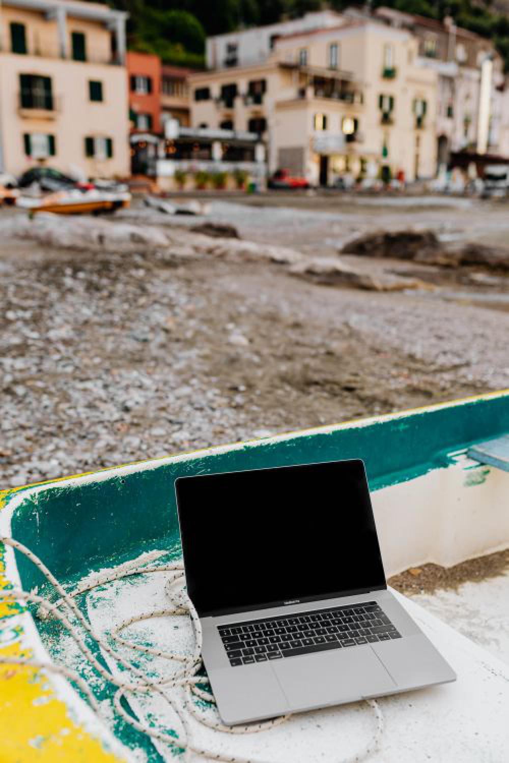 Macbook laptop on a small yellow boat on the beach Macbook laptop on a small yellow boat on the beach