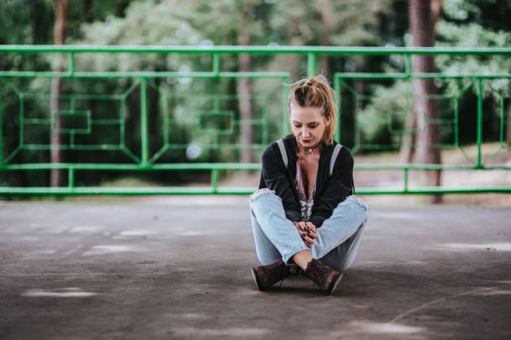 Blonde woman in a black jacket and ripped jeans by a green handrail Blonde woman in a black jacket and ripped jeans by a green handrail