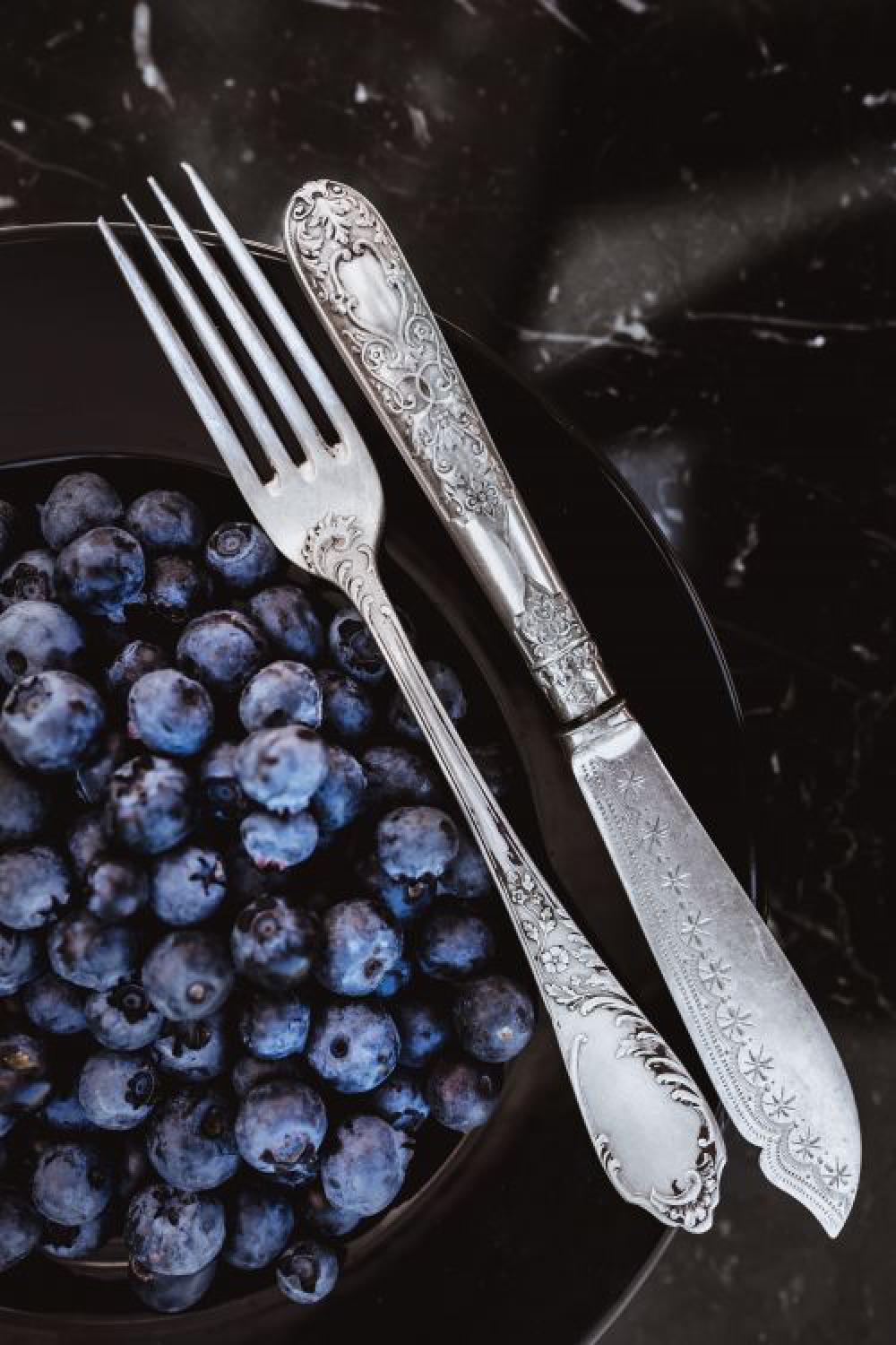 Fresh blueberries on a black plate with vintage cutlery Fresh blueberries on a black plate with vintage cutlery