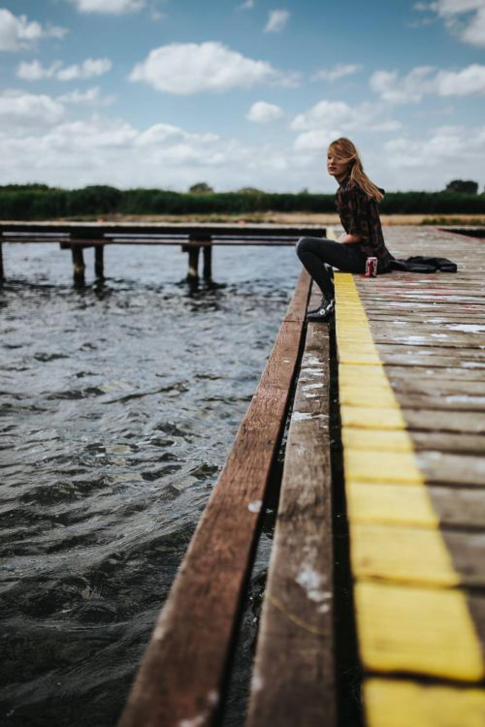 Beautiful blonde woman on a wooden pier by the lake Beautiful blonde woman on a wooden pier by the lake