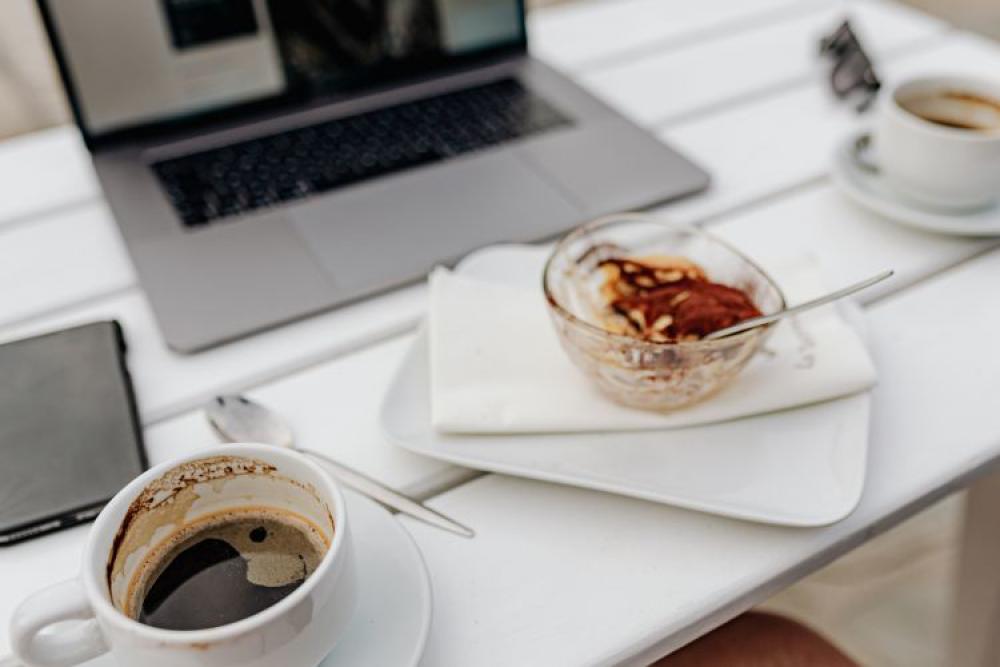 Working with a laptop by the sea. Cup of coffee and delicious tiramisu, Marina di Puolo, Italy Working with a laptop by the sea. Cup of coffee and delicious tiramisu, Marina di Puolo, Italy