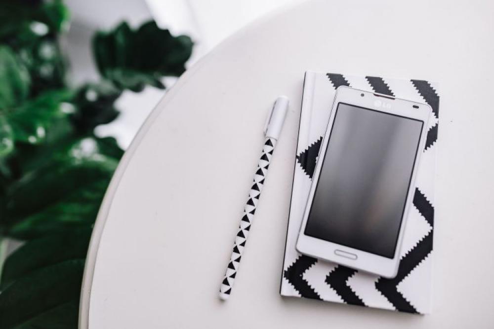 Black-and-white notebook and a white smartphone with various items Black-and-white notebook and a white smartphone with various items