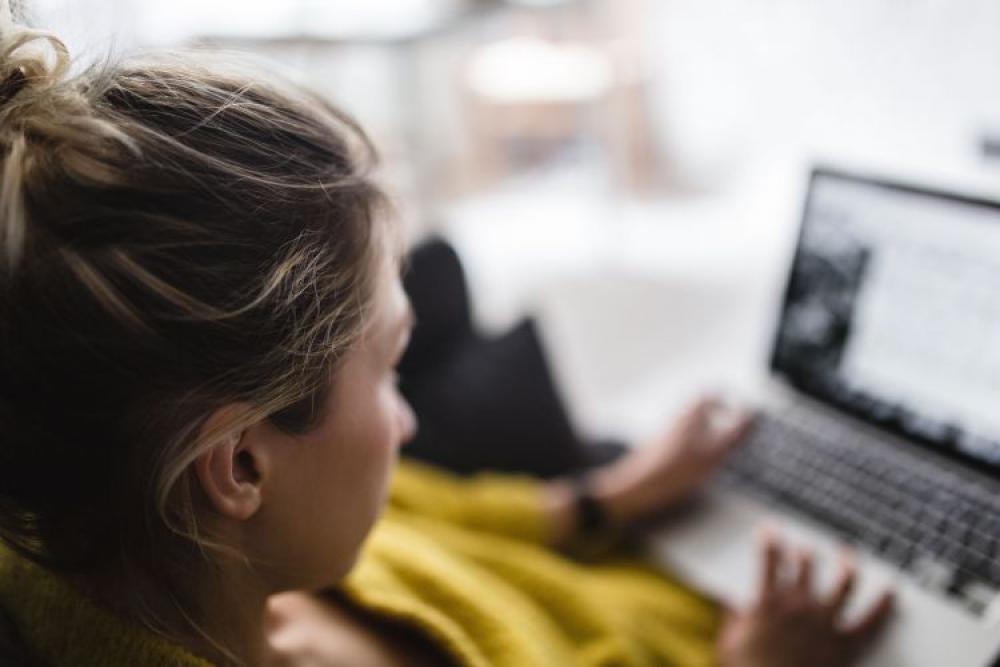 Young woman sitting on the sofa and working on her laptop Young woman sitting on the sofa and working on her laptop