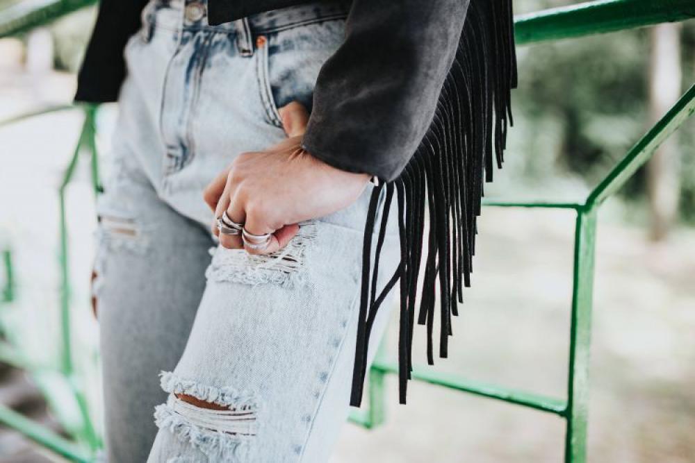 Blonde woman in a black jacket and ripped jeans by a green handrail Blonde woman in a black jacket and ripped jeans by a green handrail