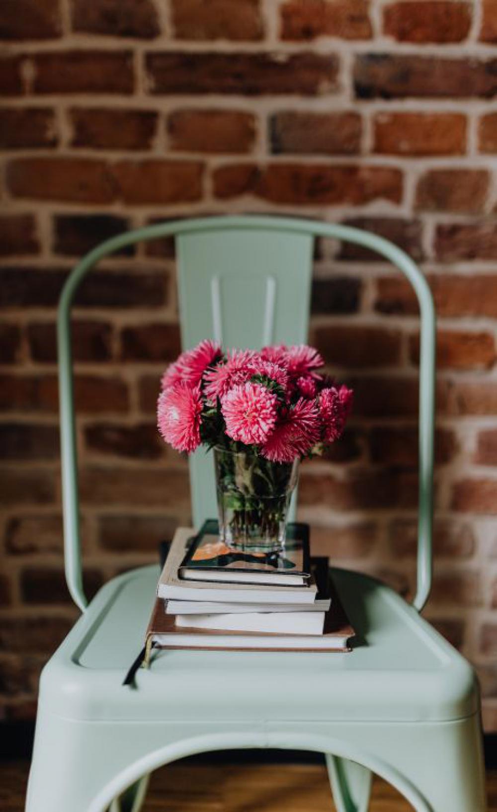 Industrial metal chair with a bouquet of pink flowers and books on it Industrial metal chair with a bouquet of pink flowers and books on it