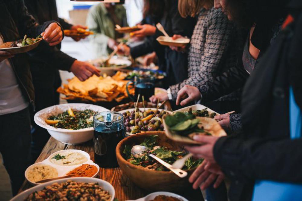 People by a banquet table full with food People by a banquet table full with food