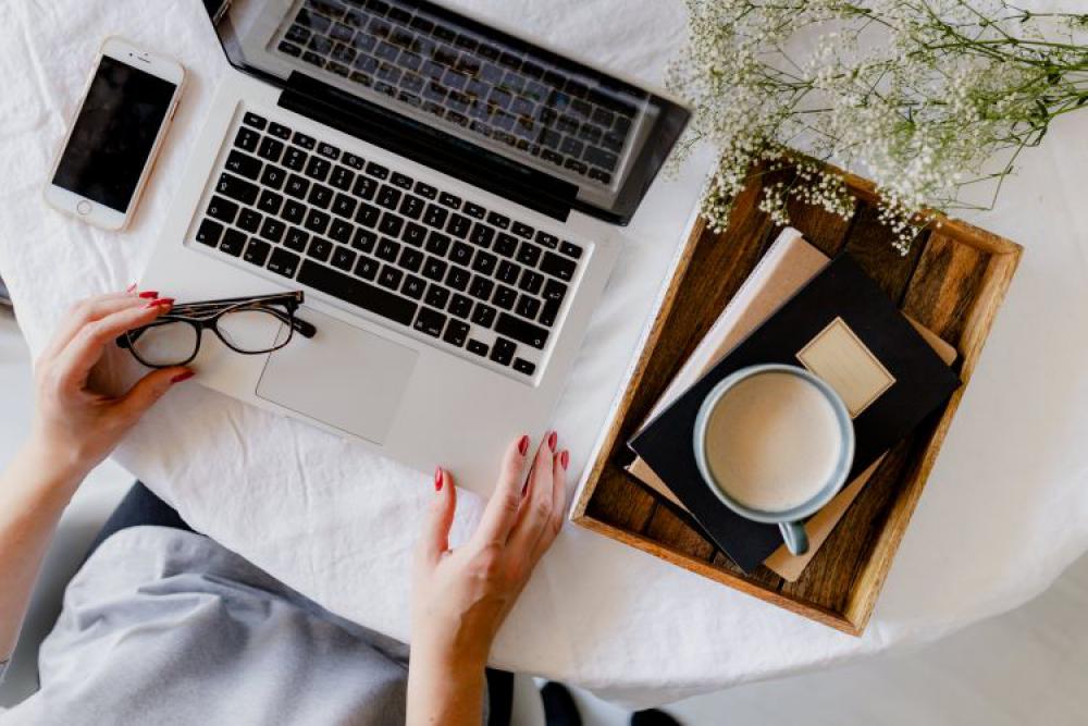 A woman works at a desk with a laptop and a cup of coffee A woman works at a desk with a laptop and a cup of coffee