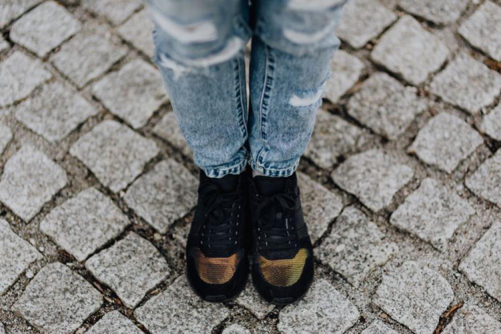 Woman in black sneakers and blue jeans Woman in black sneakers and blue jeans