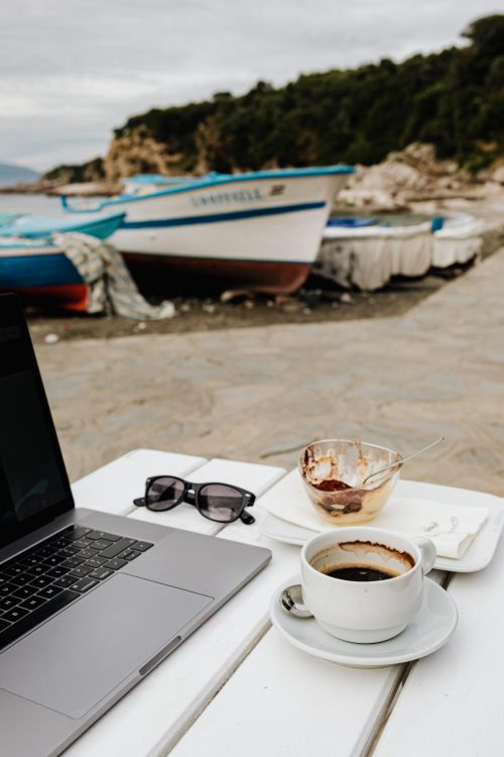 Working with a laptop by the sea. Cup of coffee and delicious tiramisu, Marina di Puolo, Italy Working with a laptop by the sea. Cup of coffee and delicious tiramisu, Marina di Puolo, Italy