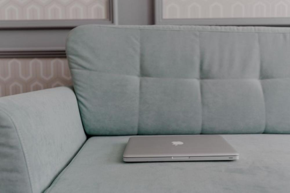 MacBook laptop lying on mint couch MacBook laptop lying on mint couch