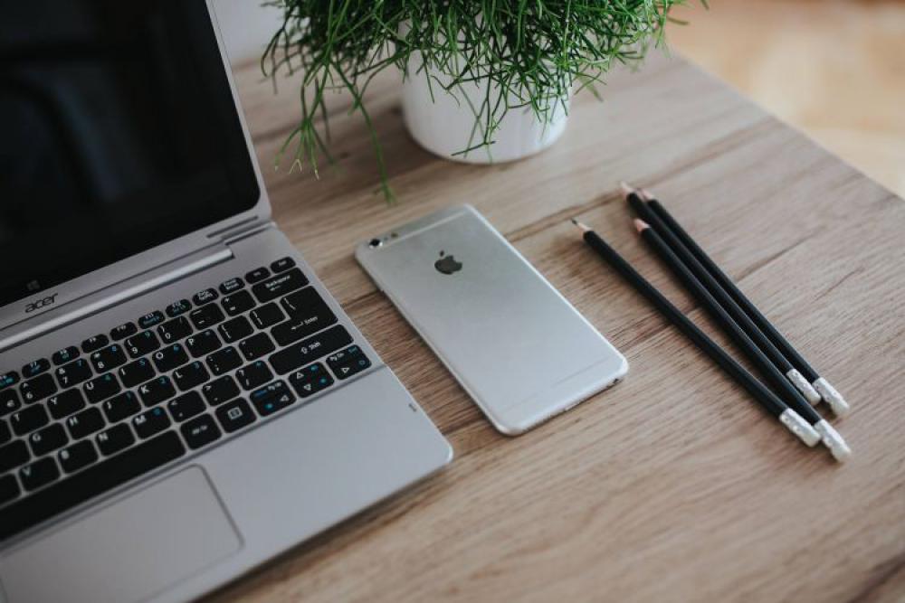 Silver Acer laptop on a wooden desk with a green plant, pencils and an Apple iPhone Silver Acer laptop on a wooden desk with a green plant, pencils and an Apple iPhone