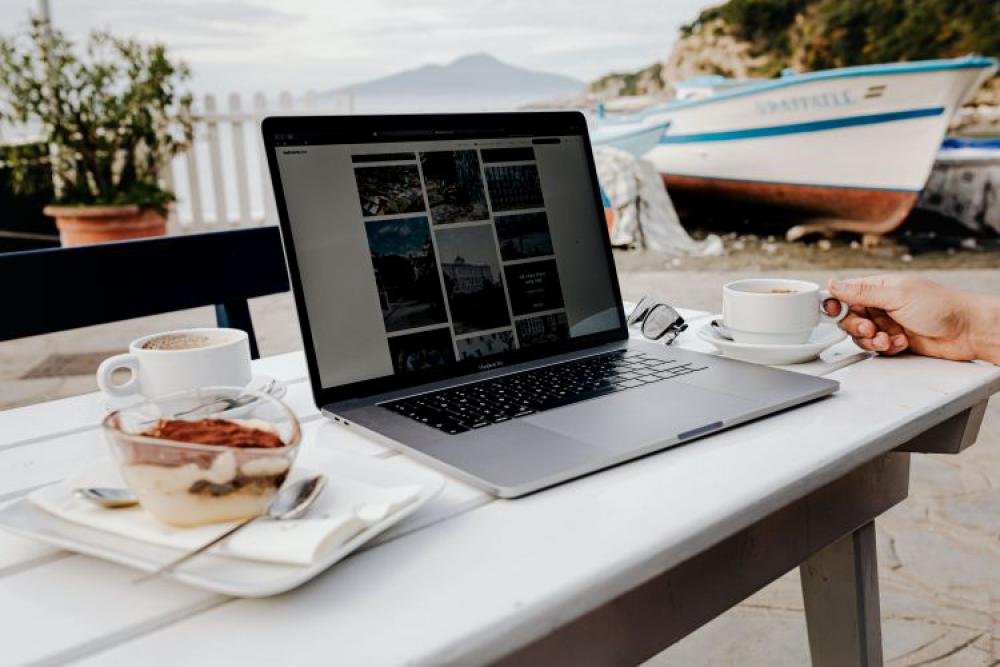 Working with a laptop by the sea. Cup of coffee and delicious tiramisu, Marina di Puolo, Italy Working with a laptop by the sea. Cup of coffee and delicious tiramisu, Marina di Puolo, Italy